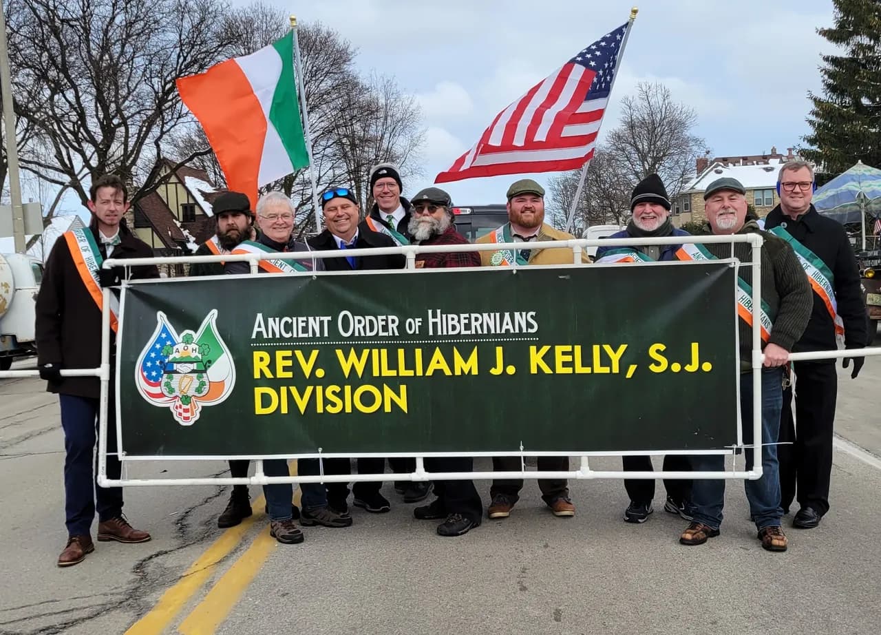 AOH Milwaukee brothers marching in the St. Patrick's Day Parade holding the Rev. William J. Kelly, S.J. Division banner with American and Irish flags